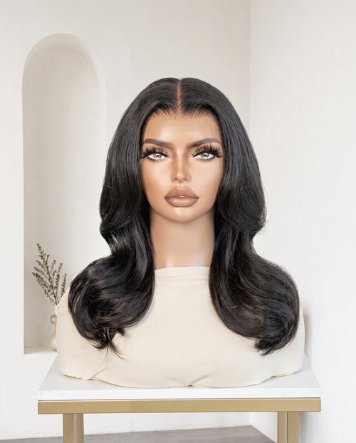 Amira natural black layered wave wig on a display stand